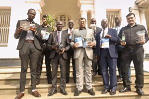 NARO Director General Dr. Yona Baguma holding a macadamia plant and the managing director Amafh Farms Mr Morvi Asim next to Dr. Baguma and other officials after the MoU signing in Entebbe